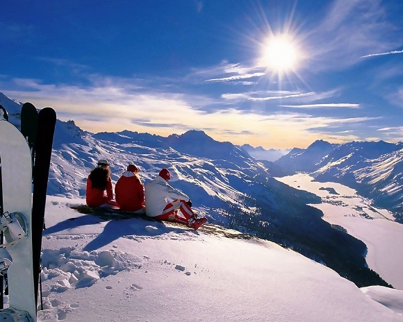 Три лыжника в горах смотрят на закат солнца